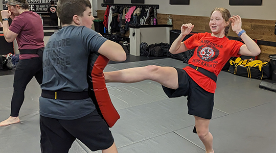 Kids Martial Arts student practicing a kicking strike technique