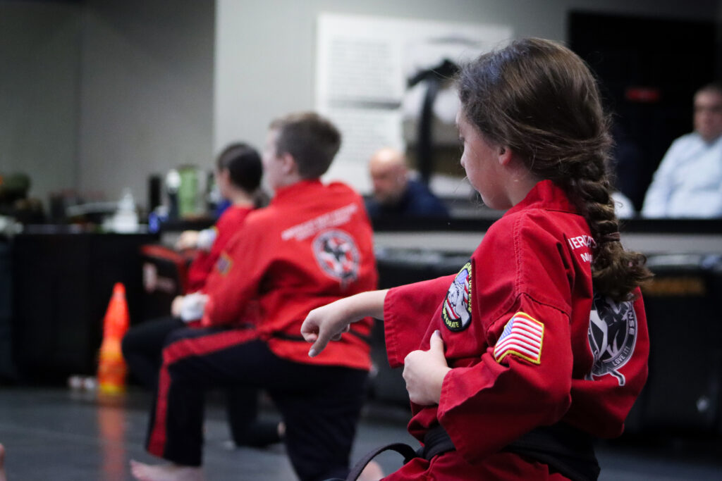 Kids wearing red gi tops and black gi pants with a red stripe practicing martial arts at America's Best Defense Martial Arts Academy.