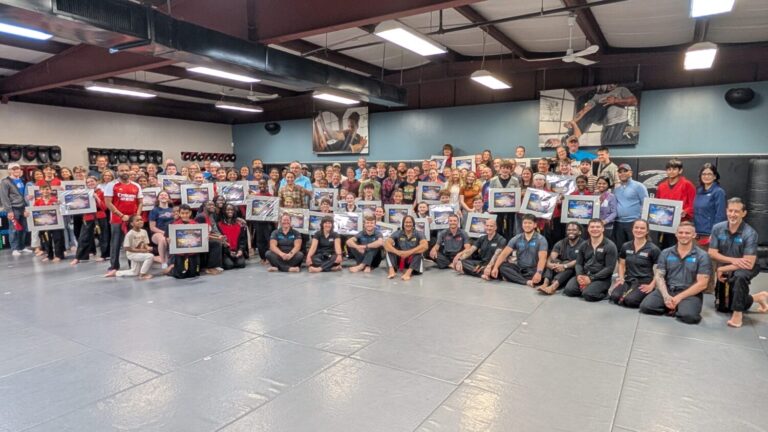 A group of martial artists pose for a picture after their black belt test.