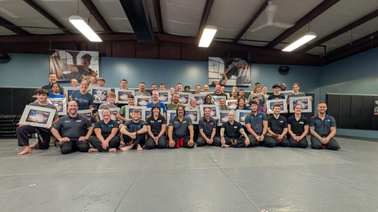 A group of martial artists pose for a picture after their black belt test.