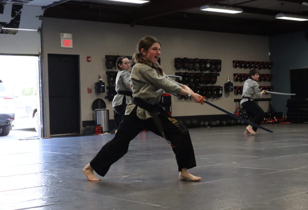 Teenage girl practices martial arts sword form at America's Best Defense